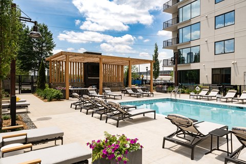 a swimming pool with lounge chairs and a building in the background